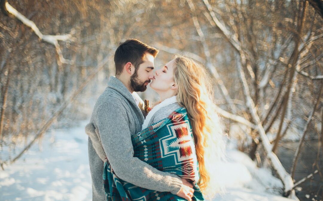 A couple holding each other in an embrace with a snowy background.